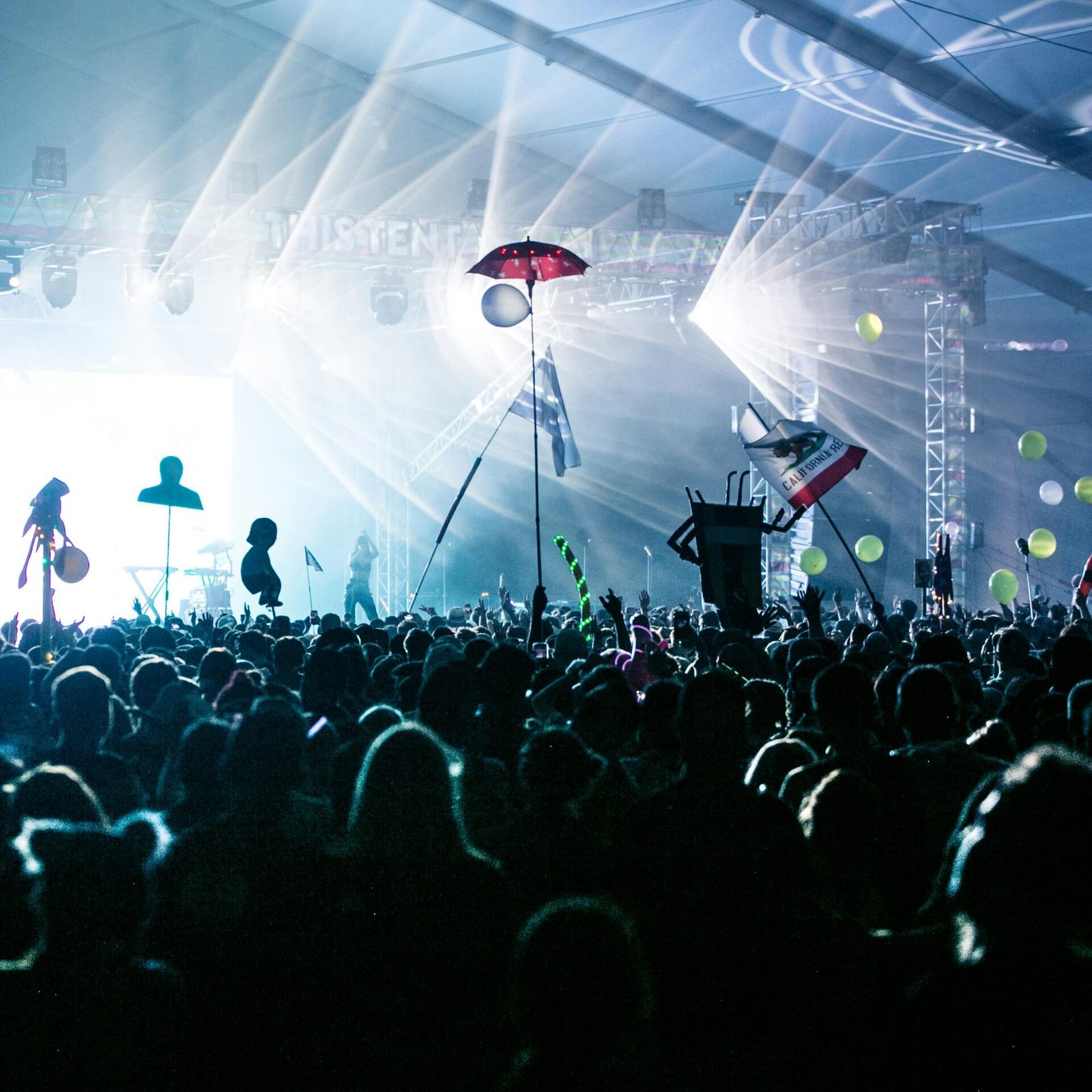 A dynamic crowd enjoying a live concert with bright stage lights and festive decorations.