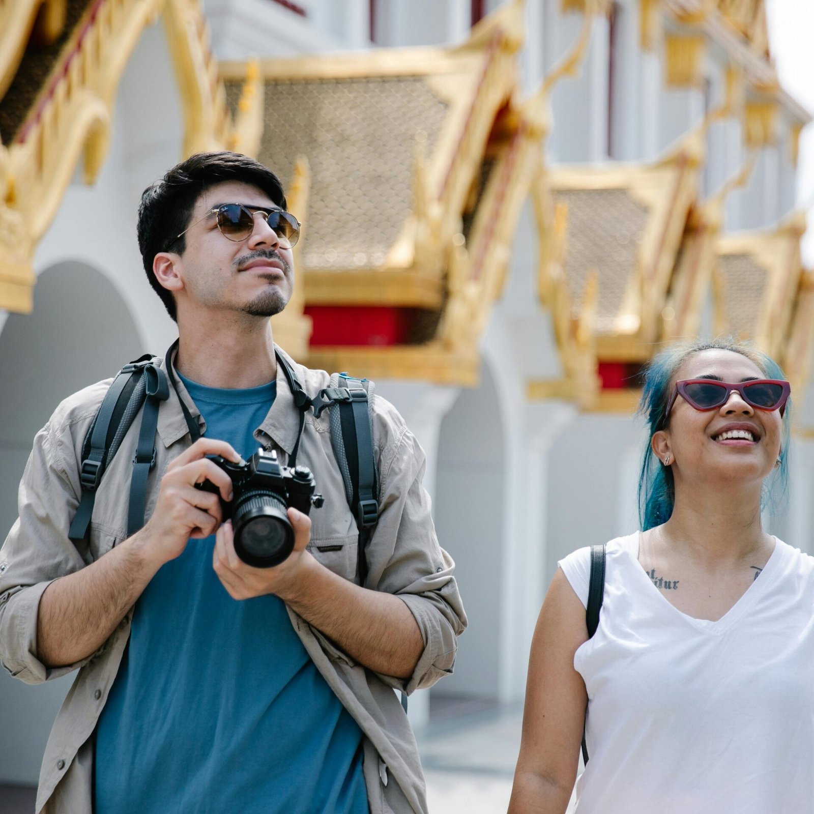 A couple explores a city's ornate architecture, capturing memories with a camera.