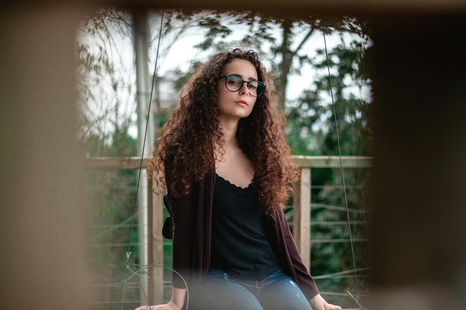 Portrait of a fashionable woman with curly hair and glasses posing outdoors in Rio do Sul, Brazil.